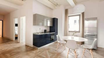 Una cocina moderna con una isla central, sillas de comedor blancas y un amplio ventanal que proporciona luz natural.