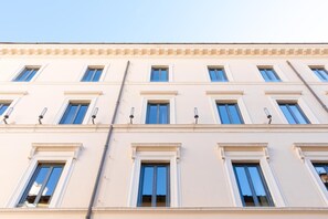 Ein mehrgeschossiges Gebäude mit einer symmetrischen Fassade, gleichmäßig angeordneten Fenstern und einem zentralen Eingang.