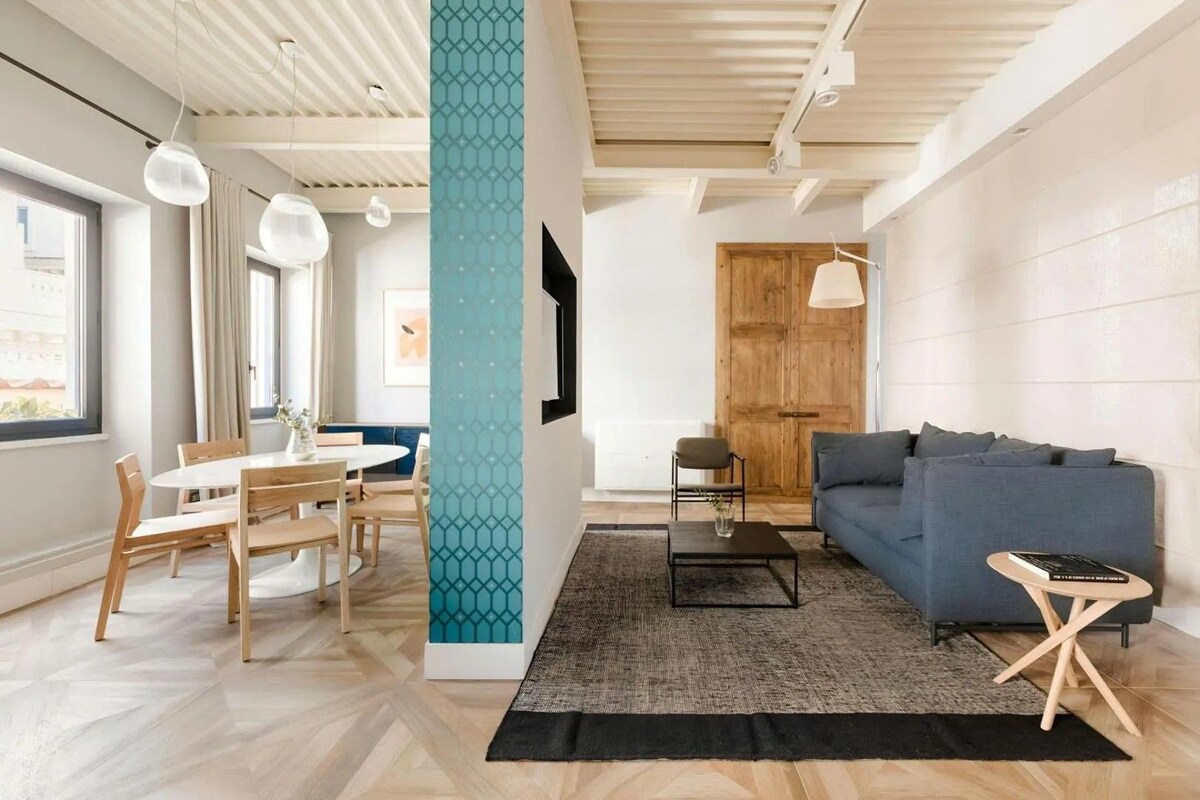 Ein modernes Wohnzimmer mit Essbereich, Holzboden und einem großen Fenster, das für natürliches Licht sorgt.