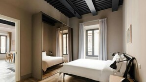 A modern hotel room with a large mirror, a bed, a bedside table with a lamp, and a window with curtains. - Numa Rome Via Veneto (Roma)