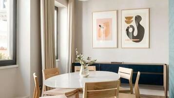 Zona pranzo con tavolo rotondo, sedie in legno, illuminazione a sospensione e opere d'arte alle pareti.