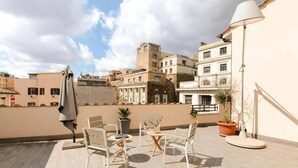 A rooftop terrace with outdoor furniture, a lamp, and potted plants. - Numa Rome Via Veneto (Roma)