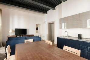 A modern living room with a sofa, a TV, and a wooden dining table.