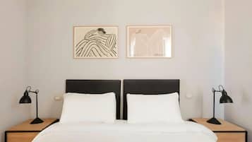 A double bed with two nightstands, each with a lamp, and two framed artworks on the wall.
