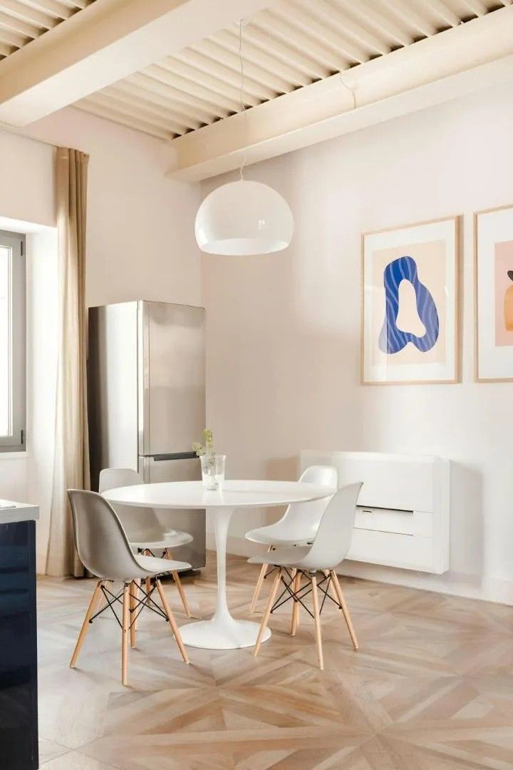 Un comedor moderno con una mesa redonda, dos sillas y una lámpara colgante.