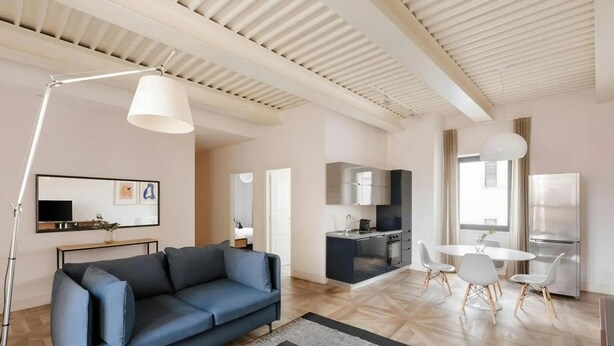 A modern living room with a sofa, coffee table, and a dining area with chairs. - Numa Rome Via Veneto (Roma)