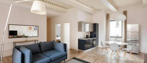 Una sala moderna con sofá, mesa de centro y zona de comedor con sillas.