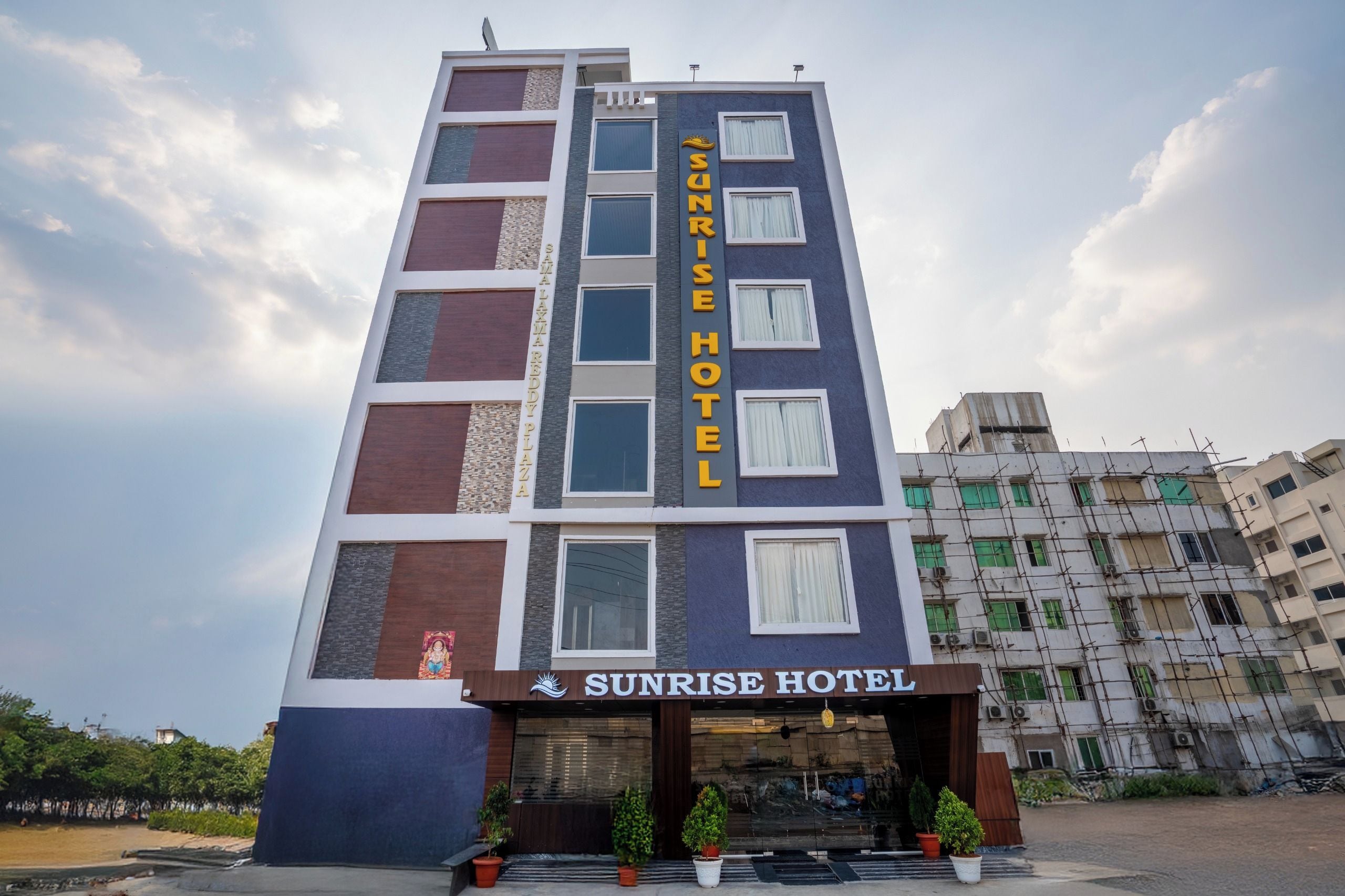 Un hotel de varios pisos con un cartel llamativo que dice 'Sunrise Hotel'.