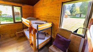 A cabin with a bunk bed, a small table, and a wicker chair. - Gîtes Le grand Renaud (Le Bourg-d'Oisans)