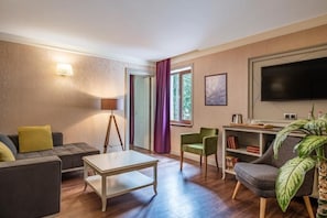Una sala de estar con un sofá, una mesa de centro, una lámpara, un televisor y una estantería.