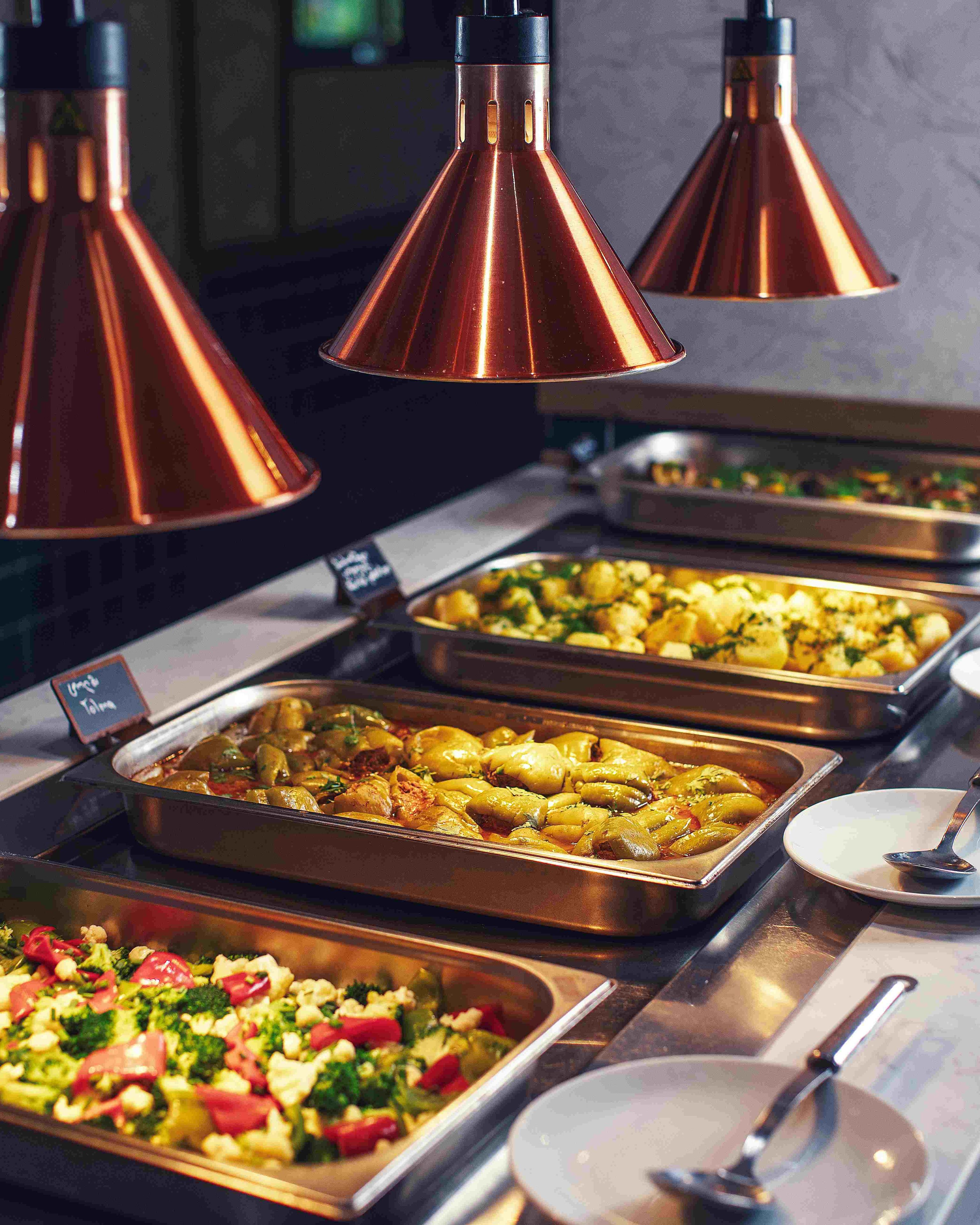 En buffet med forskellige retter og kobberfarvede hængelamper.