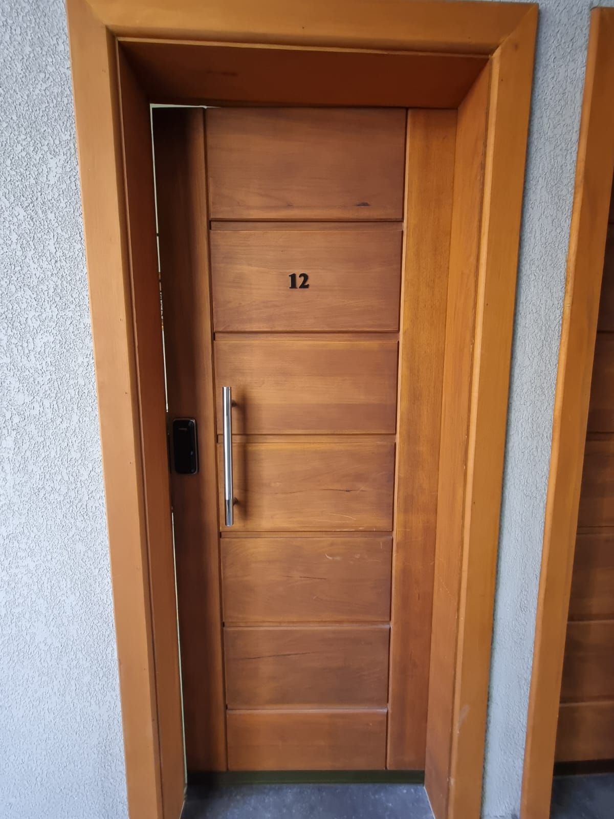 Uma porta de madeira com o número 12, uma maçaneta e uma pequena janela.