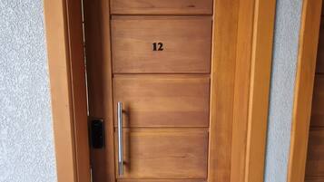 Uma porta de madeira com o número 12, uma maçaneta e uma pequena janela.