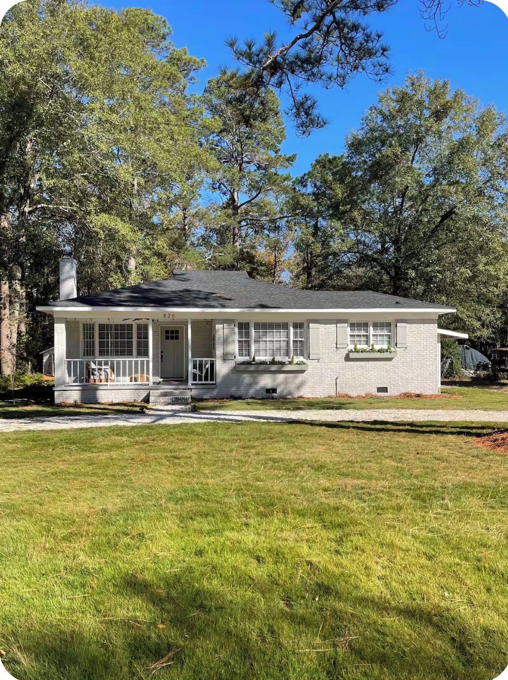A single-story house with a front porch, a chimney, and a well-maintained lawn.