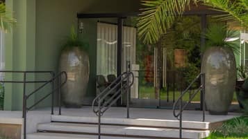 A modern building entrance with a covered porch, large decorative vases, and a staircase leading to the entrance.