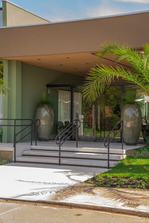 A modern building entrance with a covered porch, large decorative vases, and a staircase leading to the entrance. - Essence Paradise Pousada Charme (Bonito)