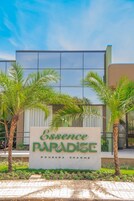 Un letrero de 'Essence Paradise' con palmeras al frente.