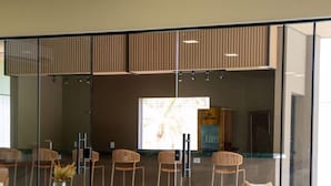 A modern interior with a seating area, a glass partition, and a sign indicating an exit. - Essence Paradise Pousada Charme  (Bonito)