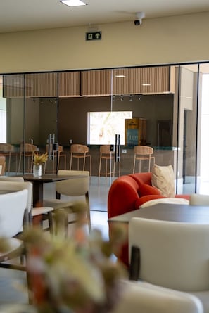 A modern interior with a seating area, a glass partition, and a sign indicating an exit. - Essence Paradise Pousada Charme (Bonito)