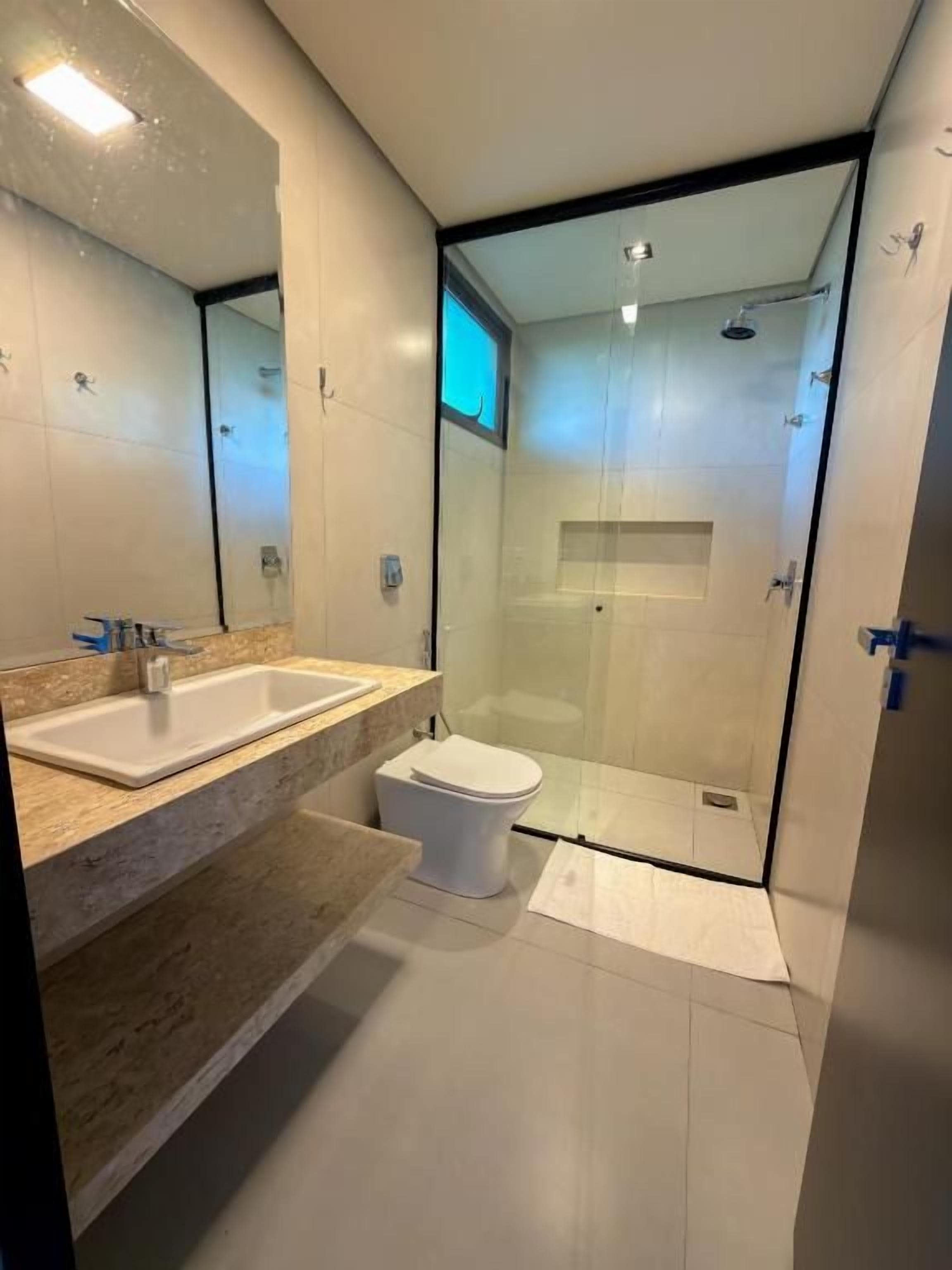 A modern bathroom with a glass shower enclosure, a white toilet, and a dual sink vanity.