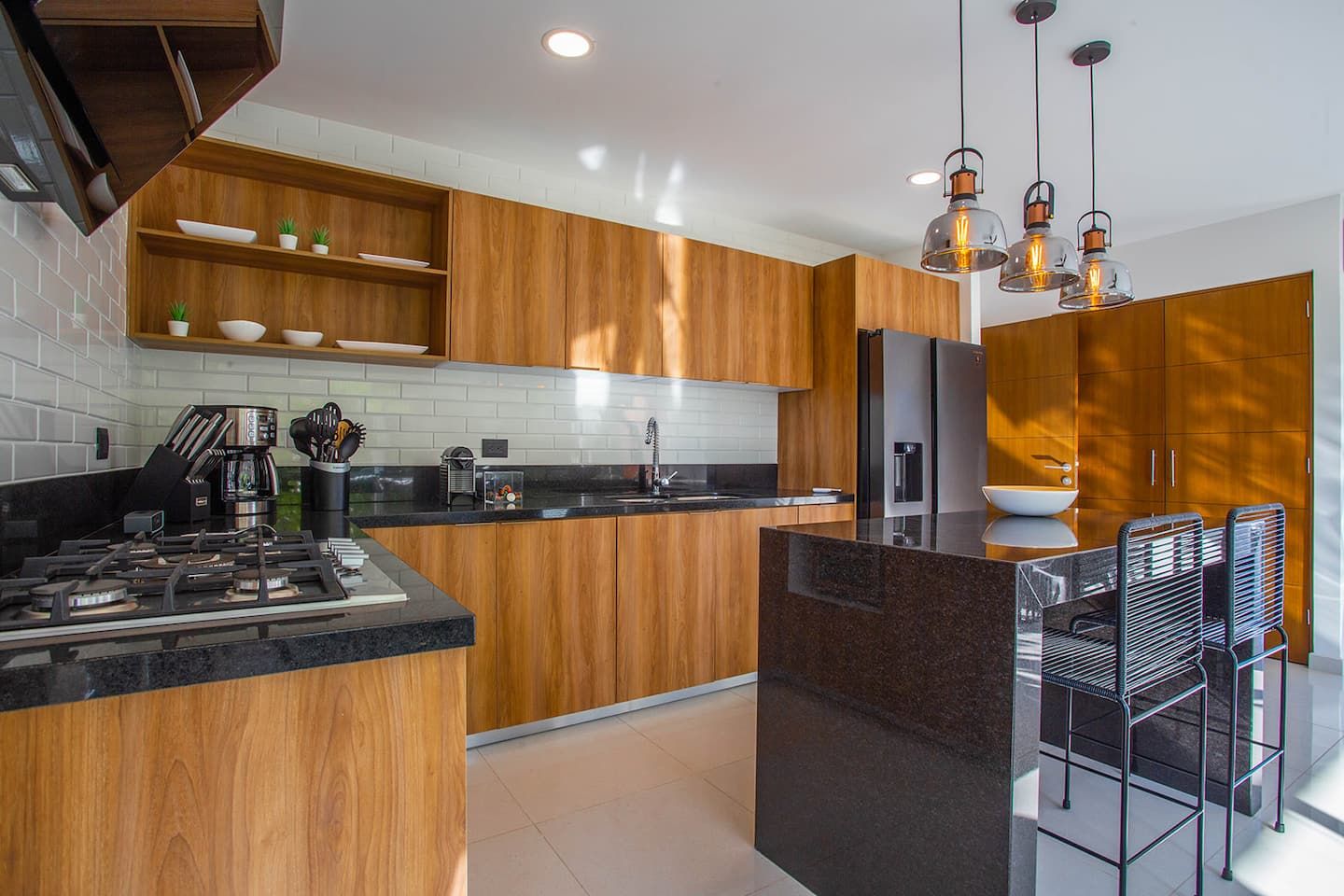 Een moderne keuken met houten kastjes, een zwart aanrecht, een gasfornuis en een ingebouwde oven.