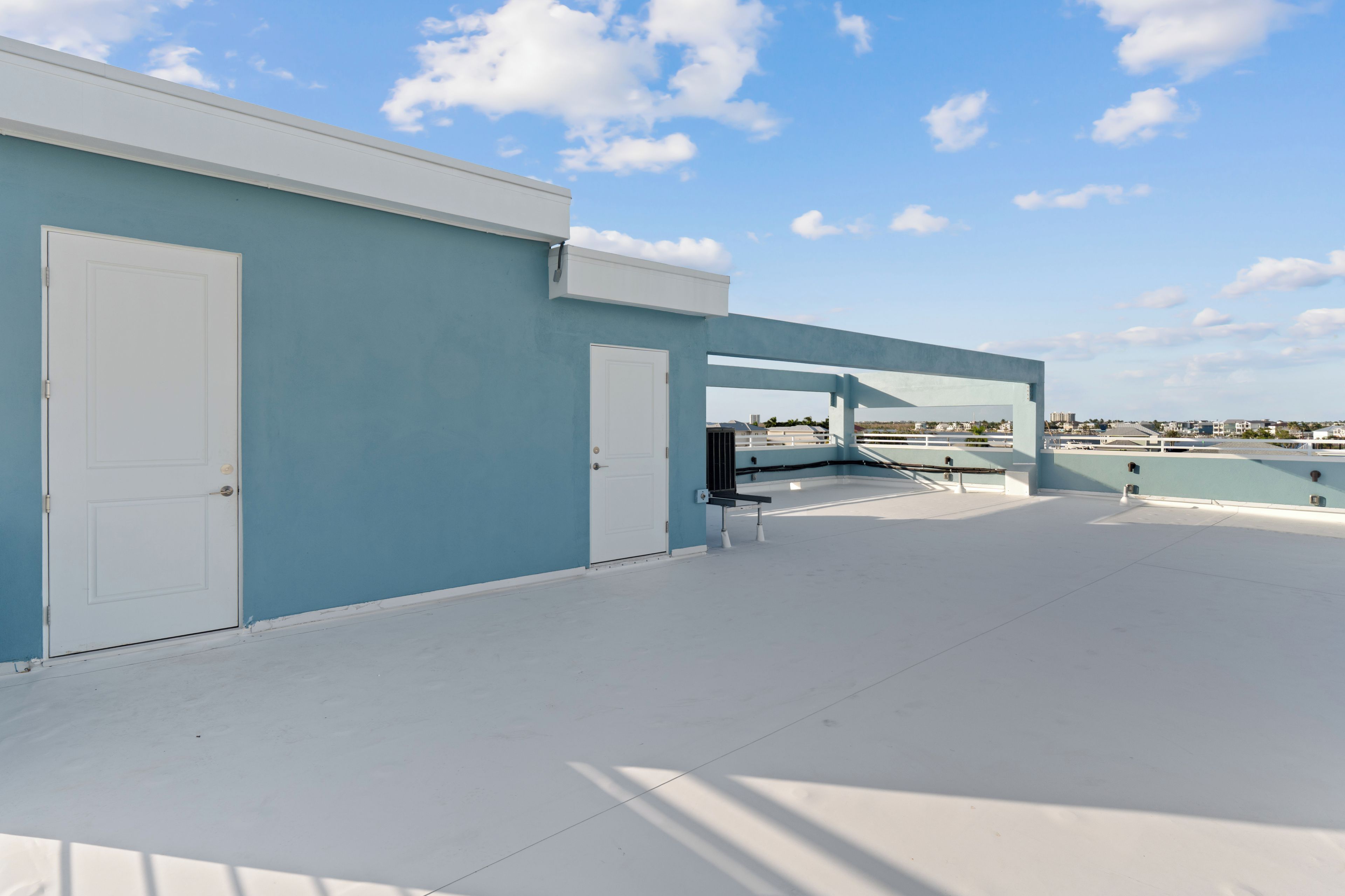 Una terraza en la azotea con cielo despejado, una puerta blanca y vistas de la ciudad.