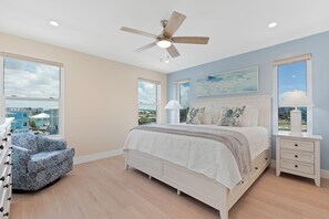 Ein Schlafzimmer mit einem Bett, einem Sessel, einem Nachttisch und einem Deckenventilator.