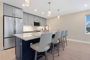 A modern kitchen with stainless steel appliances, a central island with bar stools, and pendant lighting. - 🏖️ Salty Seahorse | Duplex with Heated Pool + Rooftop Sunset Deck (Fort Myers Beach)