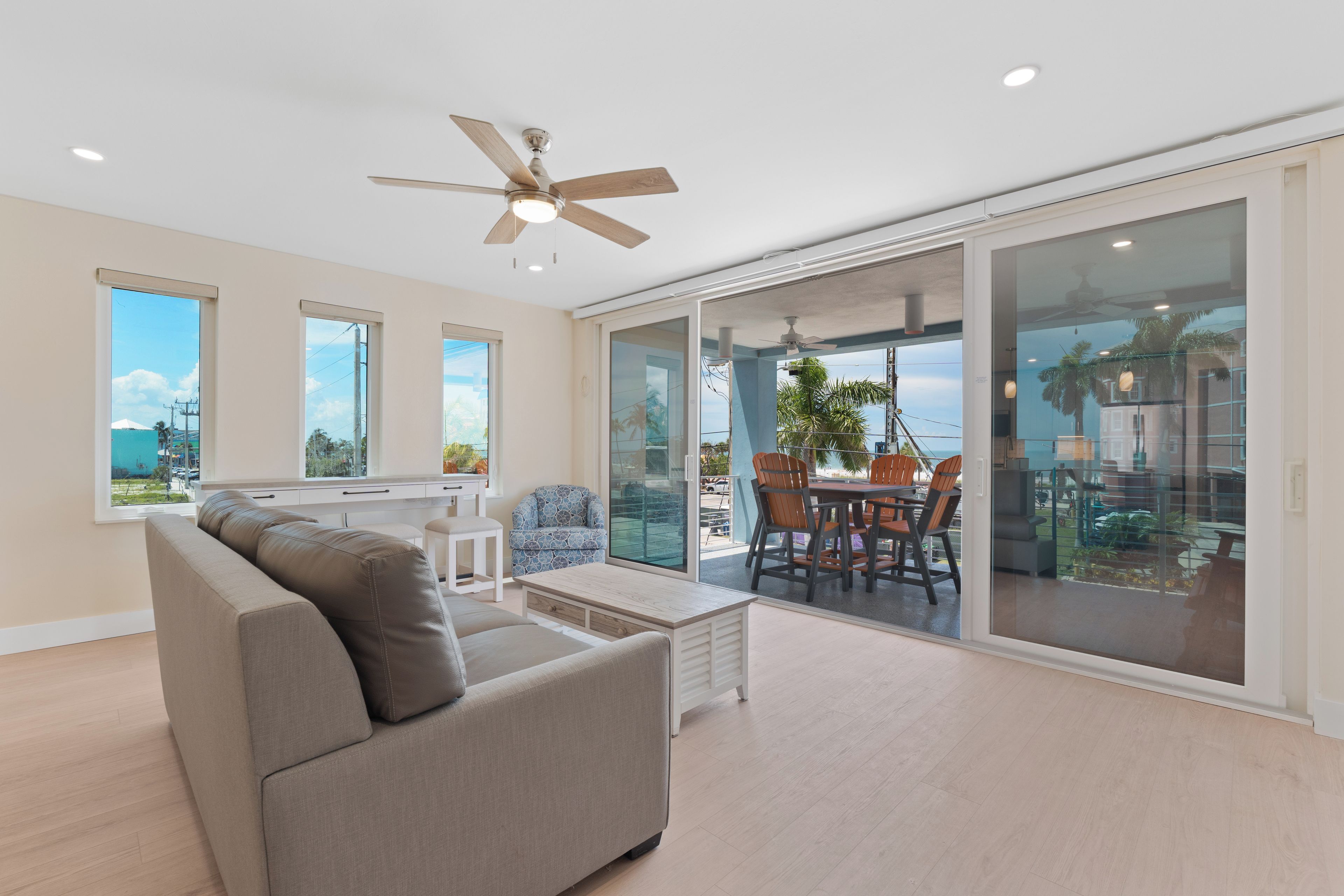 A modern living room with a sofa, a dining table with chairs, and a ceiling fan.