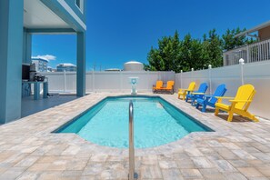 Ein Swimmingpool mit Sprungbrett, umgeben von Liegestühlen und einem weißen Zaun.