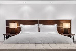 A modern bedroom with a large bed, two bedside tables with lamps, and a wooden headboard. - The Wavefront | Gulf-front Executive Residence (St. Pete Beach)