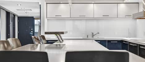 Une cuisine moderne dotée d’un grand îlot central, de meubles blancs et d’appareils électroménagers en acier inoxydable.
