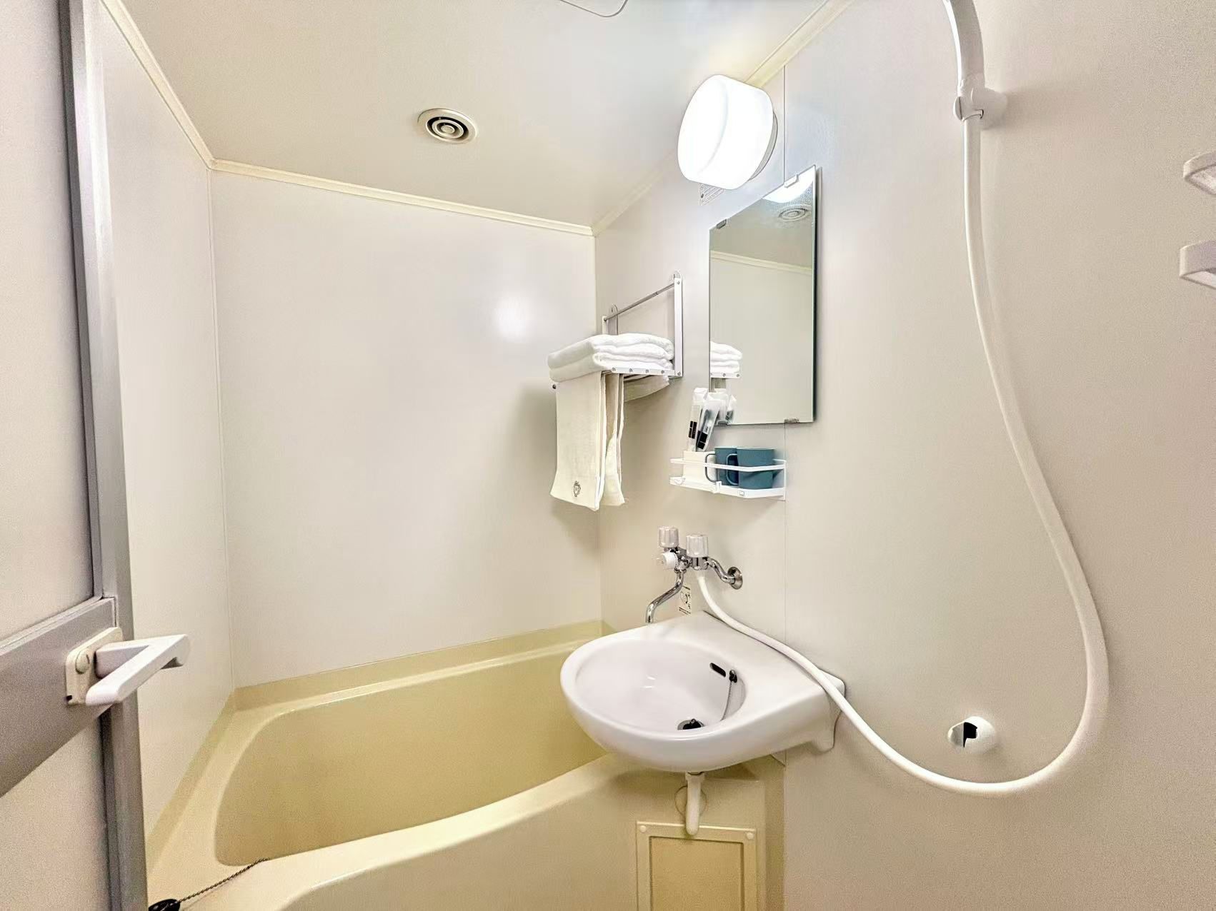 A bathroom with a bathtub, a sink, a mirror, and a towel rack.