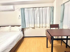 A room with a bed, a table, and a chair. There is a window with curtains. - TOGA HOTEL Showamachi (Kita-ku)