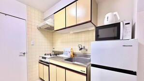 A compact kitchen with a stove, sink, and a Hisense refrigerator. - TOGA HOTEL Showamachi (Kita-ku)