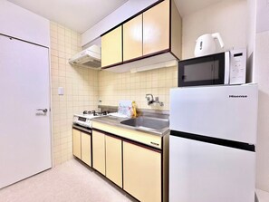 A compact kitchen with a stove, sink, and a Hisense refrigerator. - TOGA HOTEL Showamachi (Kita-ku)