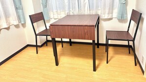 A room with a wooden table and two chairs, a light-colored floor, and a window with curtains. - TOGA HOTEL Showamachi (Kita-ku)