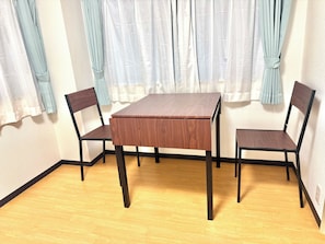 A room with a wooden table and two chairs, a light-colored floor, and a window with curtains. - TOGA HOTEL Showamachi (Kita-ku)