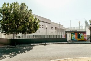 A modern building with a white fence, a tree in front, and a colorful mural on the side. - 01 Padel & BBQ Penthouse by Abarzo (Marbella)