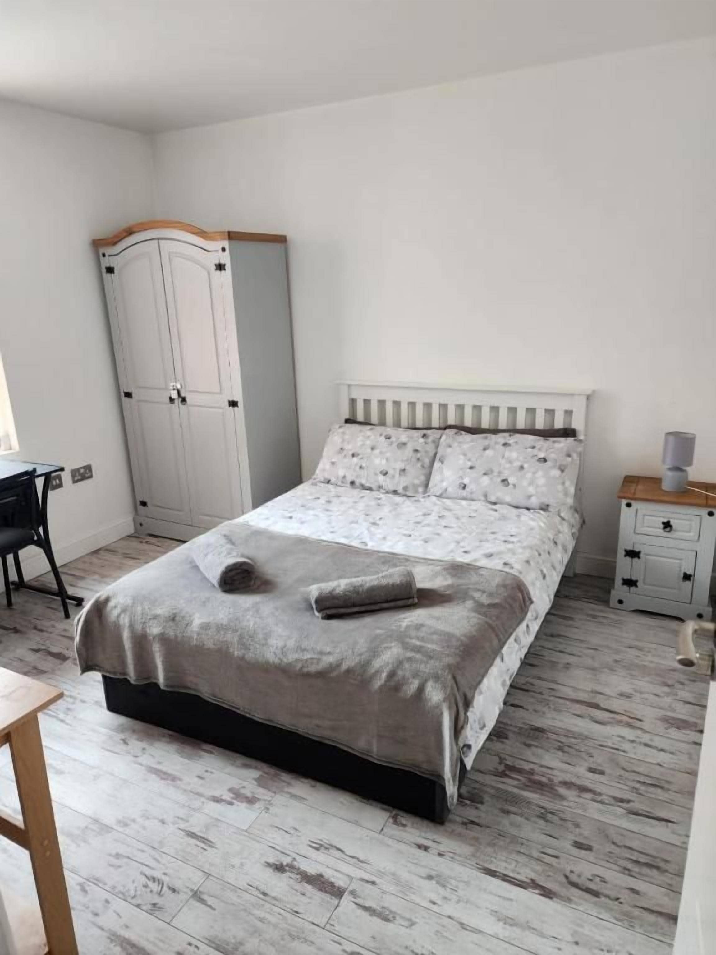Un dormitorio con cama, armario, mesita de noche y una silla.