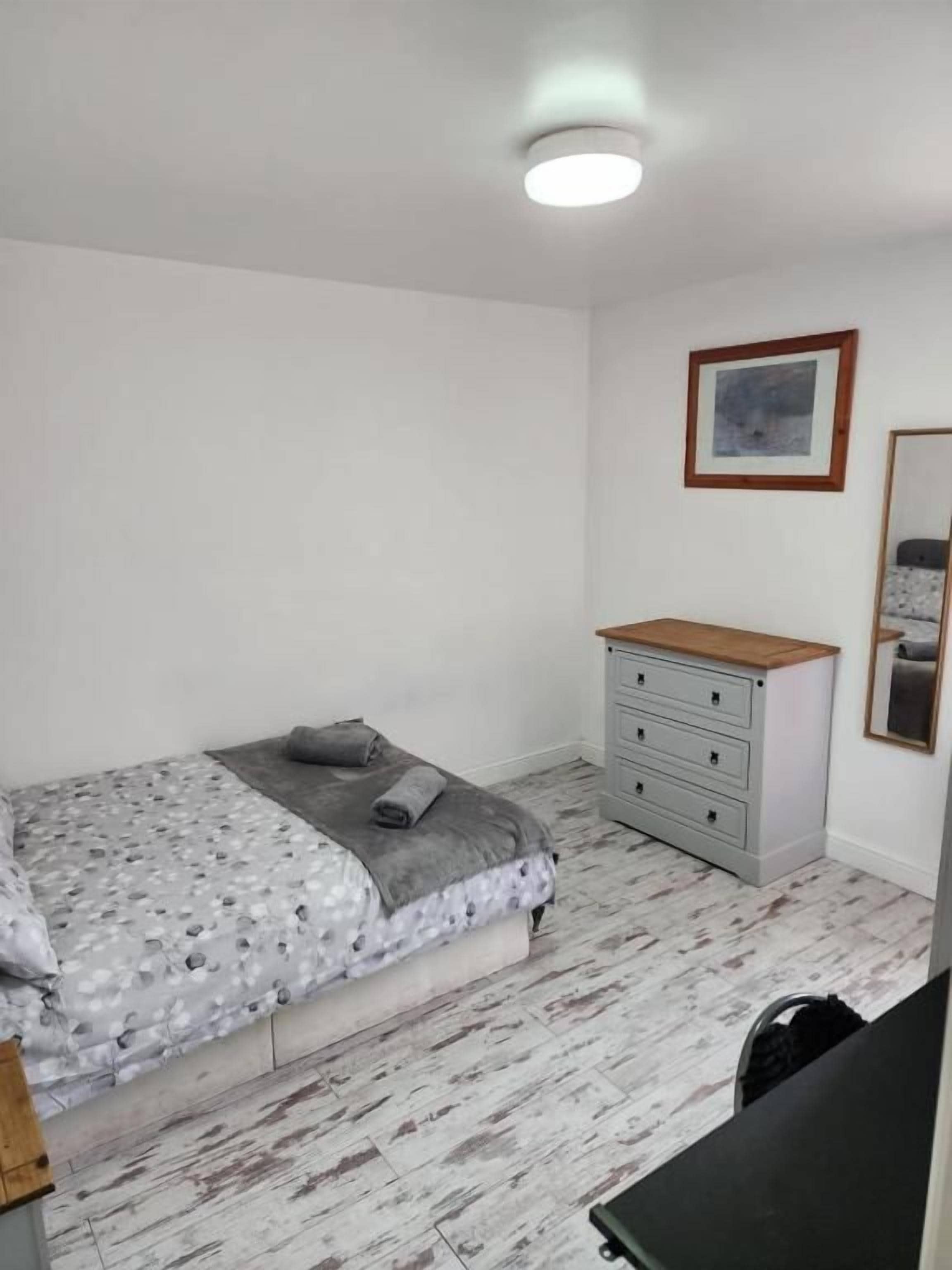 A bedroom with a bed, a dresser, and a framed picture on the wall.
