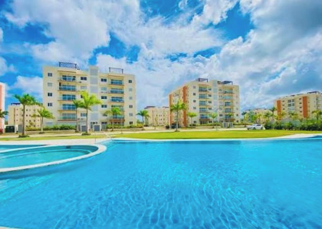 Una piscina sotto un cielo azzurro limpido, con edifici a più piani sullo sfondo.