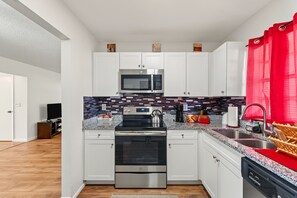 A modern kitchen with white cabinets, a stainless steel microwave, a built-in oven, and a granite countertop. - Cozy 2-bedroom house in welcoming Seminole with AC (Seminole)