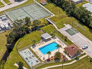 Eine Vogelperspektive auf ein Anwesen mit Schwimmbad, Tennisplätzen und einer überdachten Terrasse.