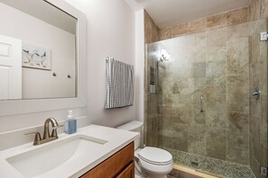 Ein Badezimmer mit Waschbecken, Spiegel, Toilette und einer Duschkabine.