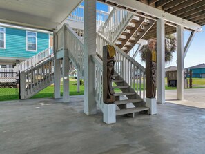 Un escalier extérieur abrité, doté d’un sol en béton, de rampes blanches et d’une main courante en métal.