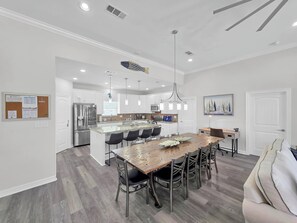 A modern kitchen with white cabinetry, stainless steel appliances, and a central island with seating. - Mer Sea, 4 bedroom 2.5 bath home sleeps 13. A short stroll to the beach. (Crystal Beach)