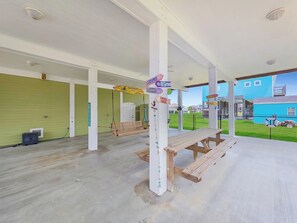 Un espace intérieur abrité, comprenant une table de pique-nique en bois, une clôture en treillis métallique et des panneaux de signalisation.