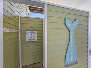 A building entrance with a sign that reads 'Sandy Toads & Salty Kisses' and a decorative mermaid tail sign that says 'Welcome.' - Mer Sea, 4 bedroom 2.5 bath home sleeps 13. A short stroll to the beach. (Crystal Beach)