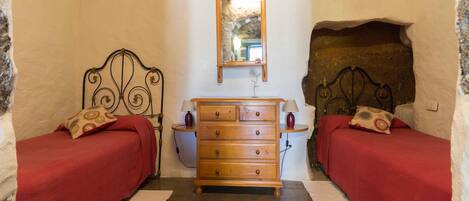 A bedroom with two beds, a dresser, and a mirror.